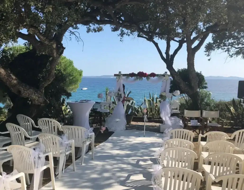 Cérémonie laïque en extérieur en Corse, arche décorée et chaises face à la mer